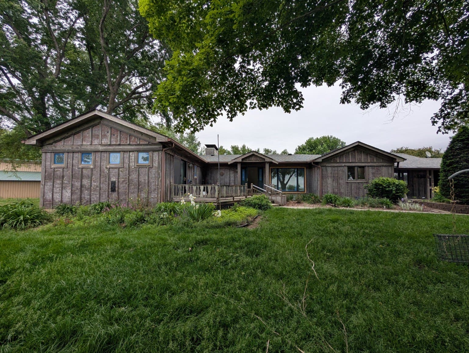 Weathered board-and-batten ranch house with an aging front deck before the makeover